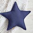 Das Sternkissen Leinen blau dunkelblau von KraftKids liegt auf einer weißen Strickdecke auf hellem Holz - ein stilvolles Accessoire für jedes Kinderzimmer.