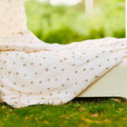 Eine Nahaufnahme eines Himmelbetts aus dem KraftKids Bettwäscheset Musselin Kirschen aus handgefertigter 100% Baumwolle mit Kirschenmuster, im Freien auf grünem Gras und verschwommenen Bäumen für erholsamen Schlaf.