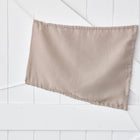 Der KraftKids Sonnensegel Musselin beige, leicht zerknittert und in einem sanften Beigeton, wird diagonal an eine weiße holzgetäfelte Wand mit sich kreuzenden Linien gepinnt.