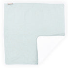 Die KraftKids Wickelunterlage Musselin goldene Punkte auf Grün ist eine rechteckige, wasserfeste Wickelunterlage mit einem kleinen seitlichen Ausschnitt, einer umgeschlagenen Ecke, die eine weiße Unterseite zeigt, und charmanten goldenen Punkten auf Grün.