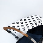 Eine Nahaufnahme des KraftKids Sonnensegel schwarze Pluszeichen Kinderwagenverdecks aus 100% Baumwolle mit schwarzen Pluszeichen und einem braunen Lenker, der optimalen Sonnenschutz vor einem schlichten weißen Hintergrund bietet.