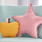 Ein hellblauer Sessel mit einem KraftKids Sternkissen Musselin rosa und einem gelben apfelförmigen Kissen verleiht diesem Kinderzimmer Charme. Im sanft sonnenbeschienenen Hintergrund ist ein Teil einer weißen Schublade zu sehen.