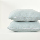 Zwei grüne KraftKids Kissenbezüge aus Musselin mit goldenen Punkten sind auf eine weiße Oberfläche gestapelt und zeigen das elegante Design vor weißem Hintergrund.