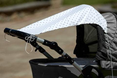 Das Sonnendach KraftKids Sonnensegel graue Punkte auf Weiss aus atmungsaktiver Baumwolle wird am Lenker des Kinderwagens befestigt und spendet an sonnigen Tagen Schatten im Freien.