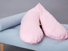 Das KraftKids qualitäts Stillkissen Streifen rosa mit ergonomischem Design ruht auf einer hellblau gepolsterten Bank mit Holzbeinen vor einem schlichten grauen Hintergrund.