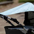 Die Nahaufnahme eines Kinderwagens zeigt das KraftKids Sonnensegel "weiße Halbkreise auf Pastelmint", das über das Verdeck drapiert ist und Ihrem Baby Sonnenschutz bietet. Der Kinderwagen steht an einem sonnigen Tag im Freien, der Hintergrund ist leicht verschwommen.