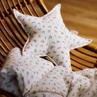 Das Sternkissen Musselin Zweige braun von KraftKids liegt auf einer passenden Decke im Holz-Wickelstuhl und setzt als zauberhaftes Detail stilvolle Akzente im Kinderzimmer vor unscharfem Holzboden.