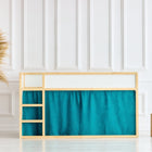 In einem hellen Kinderzimmer mit weiß getäfelten Wänden steht ein IKEA Kura Hochbett mit Leiter und KraftKids Hochbettvorhänge Set 2+1 Musselin goldene Punkte auf Petrol. Links steht eine hohe Pampasgrasvase, rechts stehen zwei Holzhocker.