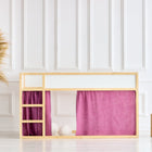 In einem hellen Zimmer mit weiß getäfelten Wänden steht ein KraftKids Hochbettvorhänge Set 2+1 Musselin purpur für das Bett Kura, das mit rosafarbenen Vorhängen und einer eingebauten Leiter gestylt ist; eine Weidenvase mit Pampasgras sorgt in der Nähe für Charme.